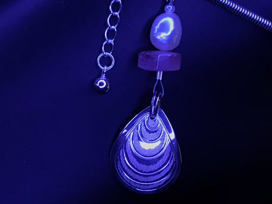 Close up on Butter Clam charm with pink tourmaline and white pearl on sterling silver anklet by Laura Dutheil.