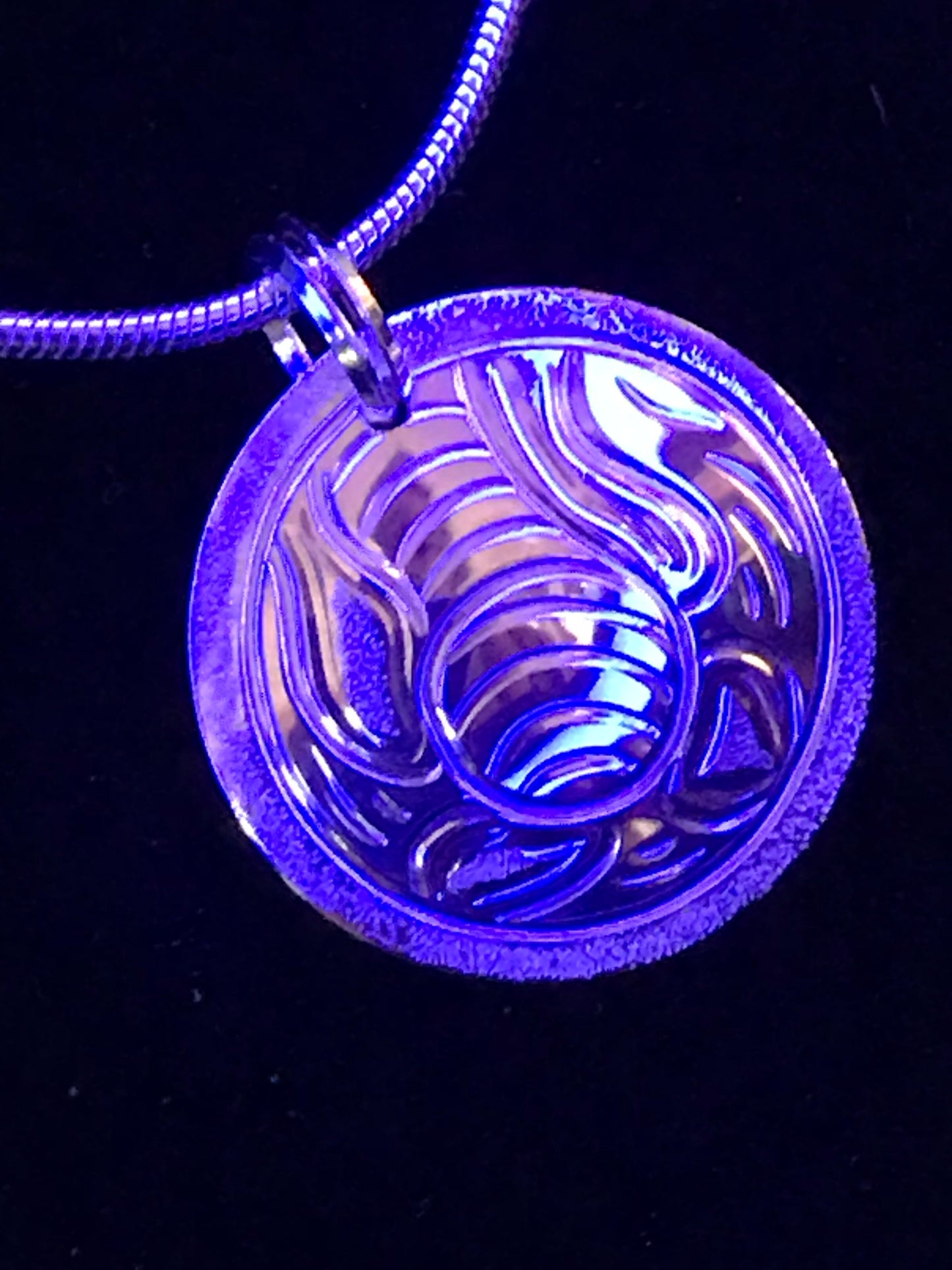 Bull Kelp pendant designed and engraved by Island artisan jeweller Laura Dutheil. Photographed in a blue light to give the effect of water.