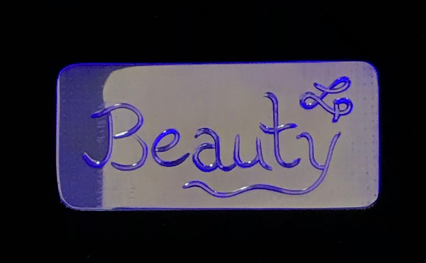 Back of Sleeping Beauty ear cuff inscribed "Beauty" by Laura Dutheil. Photo of cuff before it is formed.